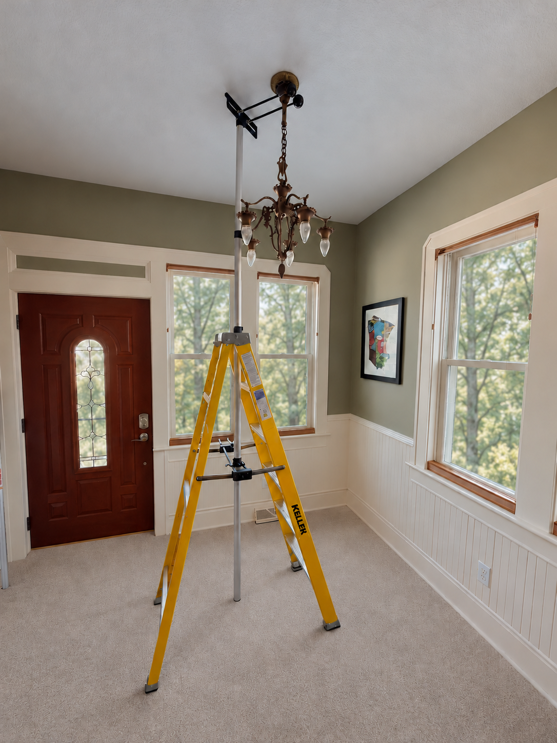 Complete Hang It Helper prototype with adjustable pole, support assembly, yellow ladder, and chandelier, visible from top to bottom